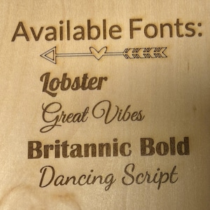 May include: A wooden sign with the text "Available Fonts:" and a list of fonts: Lobster, Great Vibes, Britannic Bold, and Dancing Script.