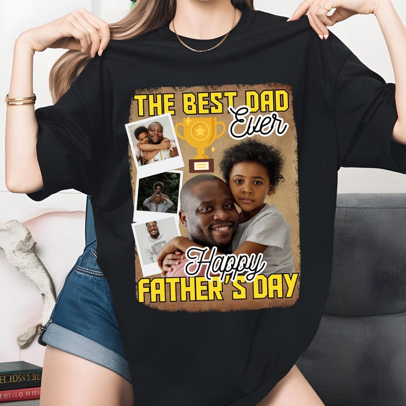 Peut inclure: T-shirt noir avec un graphisme repr&eacute;sentant un p&egrave;re et un enfant, les mots "THE BEST DAD Ever" et "Happy FATHER'S DAY". Le motif comprend un troph&eacute;e et plusieurs petites impressions photo.
