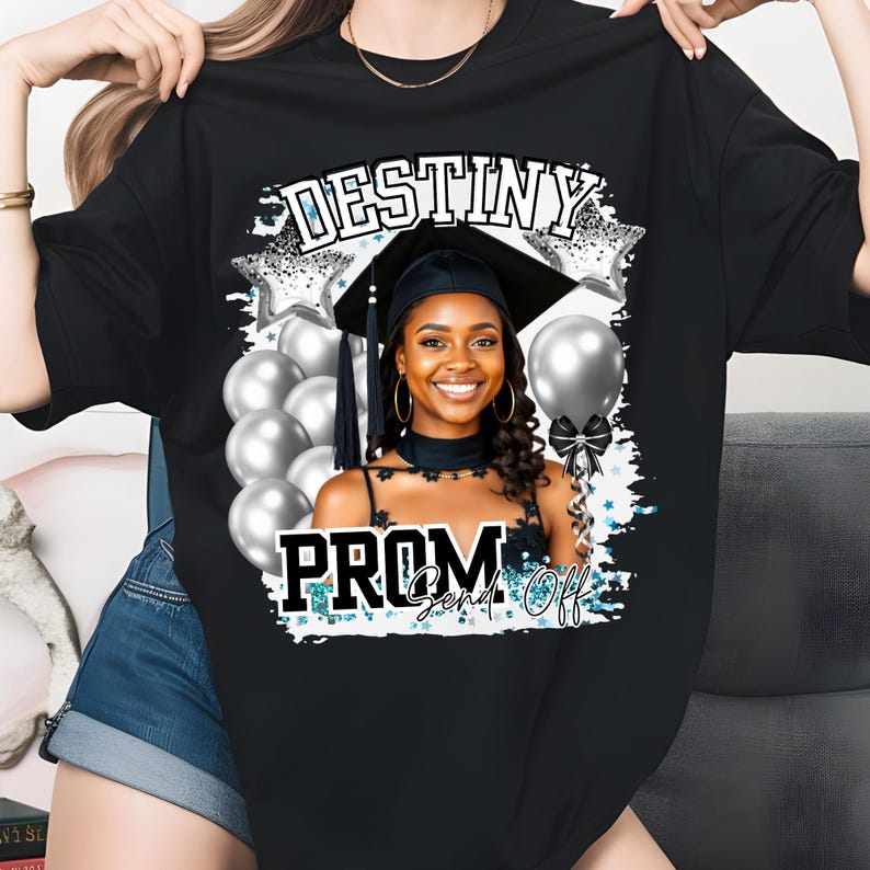Pu&ograve; includere: T-shirt nero con un design a tema laurea. Il design include il testo "DESTINY PROM Send Off" con una foto di una persona sorridente con cappello e toga di laurea, circondata da palloncini e stelle argentate.