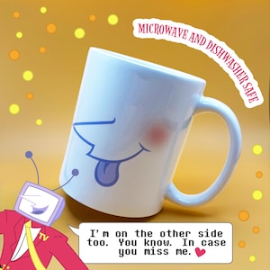 A photo of a white mug with Mr Tenna's face printed on it, sticking his tongue out playfully and blushing. The top text reads "microwave and dishwasher safe." Mr Tenna leans in from the bottom with a speech bubble that reads "I'm on the other side too. You know. In case you miss me."