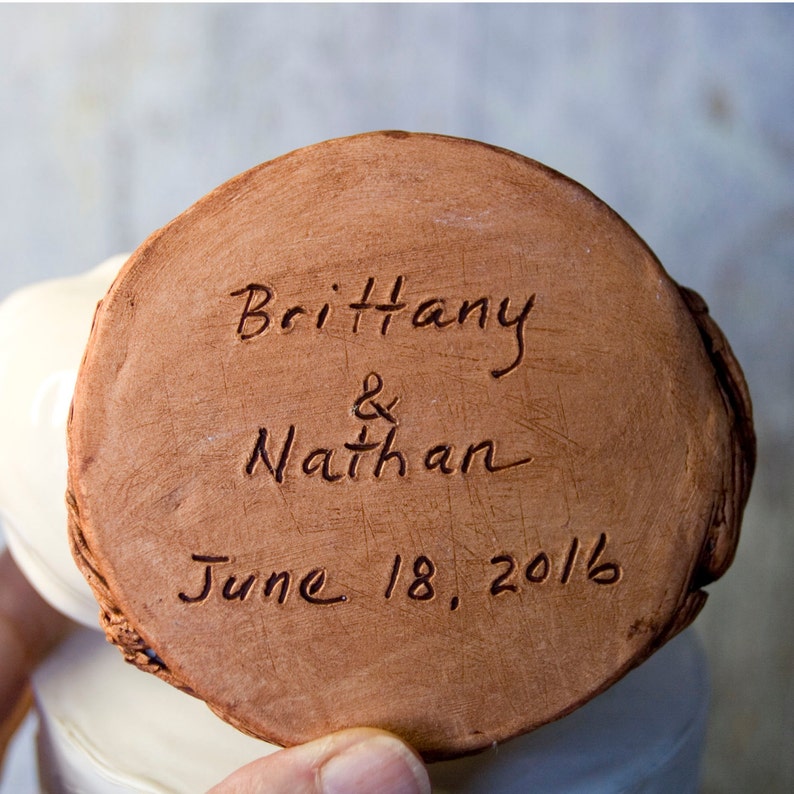 K&ouml;nnte beinhalten: Eine terracottafarbene Keramikscheibe mit der Inschrift "Brittany & Nathan June 18, 2016" in brauner Tinte.