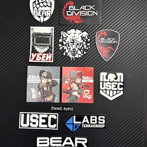 May include: A collection of rectangular and shield-shaped stickers featuring various designs including the text BEAR, BLACK DIVISION, USEC, LABS TERRAGROUP, and KILLA, alongside illustrations of a wolf, a scorpion, and anime-style characters.