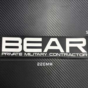 May include: A rectangular black sticker featuring the white text BEAR and the words PRIVATE MILITARY CONTRACTOR underneath. The sticker measures 220mm in width and 55mm in height as indicated by the white dimension lines and text labels.