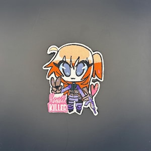 Op de afbeelding: Geborduurde patch met een anime-achtig personage met oranje haar, blauwe ogen en een vredesteken. Het personage houdt een paars geweer en een roze hart vast. De tekst "Kawaii Killer" staat eronder.