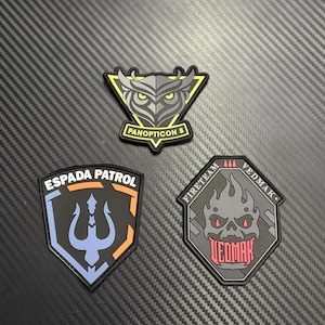May include: Three embroidered patches with unique designs. One features an owl with the text "PANOPTICON 8", another displays a trident with "ESPADA PATROL", and the last shows a skull with "VEDMAK" and "FIRETEAM".