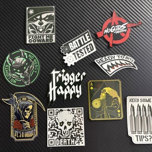 May include: A collection of ten decorative morale patches featuring various graphic designs, including a skull, a wolf, a grim reaper, bullets, and text such as Fight Me Coward, Battle Tested, No Gods No Masters, Ready To Bite, Trigger Happy, and Need Some Tips.