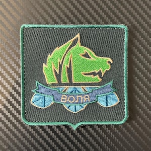 May include: Embroidered patch featuring a green wolf head design on a dark gray square. A blue banner with the word "Воля" is below the wolf. The patch has a green border.