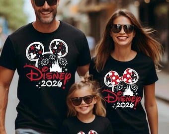 May include: Black t-shirts with a Disney theme, featuring Mickey Mouse ears, fireworks, and the text "Disney 2026" in red and white. The shirts are worn by a family of three, all wearing sunglasses.