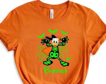 May include: Orange t-shirt with a green cartoon duck dressed as a skeleton holding a pumpkin. The duck is surrounded by bats and spiderwebs. The text "BOO-THER" is printed below the duck.