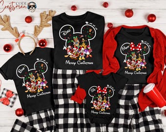 May include: Black Christmas family matching pajama sets. Each shirt features a Mickey Mouse head outline with the words "Dad", "Mom", "Bro", and "Sis". The shirts have a graphic of Disney characters and the words "Merry Christmas". The pajamas have a black and white plaid pattern.