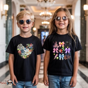 May include: Two children wearing black t-shirts and sunglasses. The t-shirts feature colorful graphic designs. One shirt has a heart-shaped design with cartoon characters. The other shirt has a design with bows and a castle.