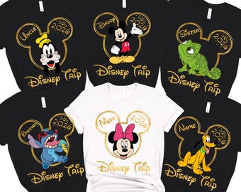 May include: Collection of black and white Disney Trip t-shirts featuring various characters like Goofy, Mickey Mouse, Stitch, and Pluto. One white shirt features Minnie Mouse. Each shirt has a family role and the year 2026.