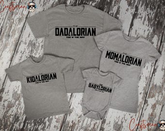 May include: Four gray t-shirts and a baby onesie with black text. The shirts read "The Dadalorian", "The Momalorian", and "The Kidalorian". The onesie says "The Babylorian". All include the phrase "This is the Way".