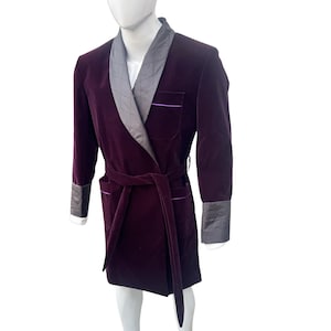 May include: A purple velvet robe with a gray satin collar and a matching sash. The robe has a purple trim and a pocket on the left side.