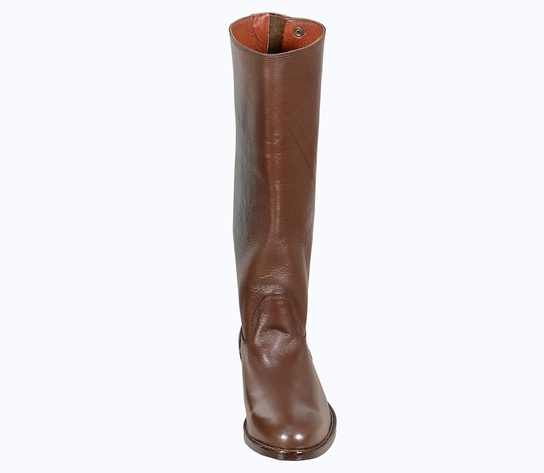 May include: A pair of brown leather riding boots with a pointed toe and a zipper on the back.