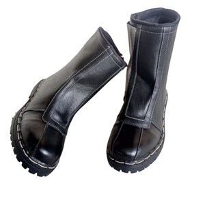 May include: A pair of black leather boots with white stitching. The boots have a zipper up the back and a pointed toe.