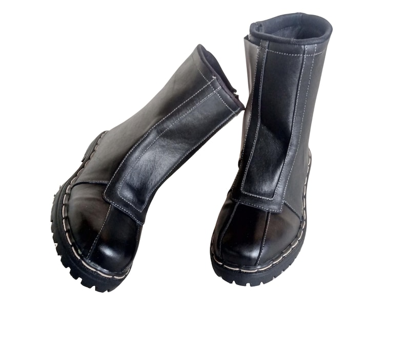 May include: A pair of black leather boots with white stitching. The boots have a zipper up the back and a pointed toe.