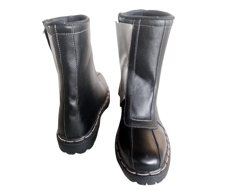 May include: A pair of black leather boots with a white panel on the side. The boots have a zipper on the inside of the ankle and a white stitch detail around the sole.