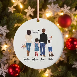 Könnte beinhalten: Weißer Keramik-Weihnachtsschmuck mit einer Familienillustration. Der Schmuck zeigt eine vierköpfige Familie mit dem Wort "Family" darüber. Die Namen "Sophie Selena John Mike" sind darunter aufgedruckt. Ein roségoldenes Band ist zum Aufhängen befestigt.