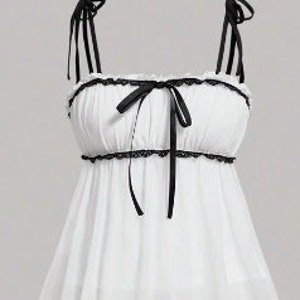 May include: White camisole with black trim and straps. The top features a ruffled neckline and a bow detail at the center. The straps are adjustable and tie at the shoulders. The fabric appears lightweight and flowy.