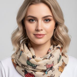 May include: A beige infinity scarf with a repeating pattern of dachshund dogs in various outfits. The dogs are in different colours, including red, green, and blue. The scarf is wrapped around a person's neck.