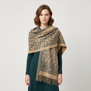 May include: A grey and tan leopard print scarf with a fringed edge. The scarf is draped over the shoulders. The scarf has a tan border.