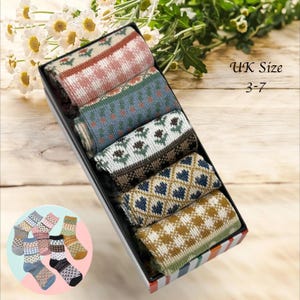 May include: A gift box with six pairs of patterned socks. The socks display diverse designs in shades of red, blue, and brown. The text "UK Size 3-7" is visible. A smaller image shows additional sock designs.