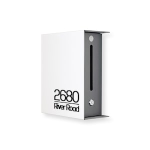 Könnte beinhalten: Ein moderner weißer Briefkasten mit einer dunkelgrauen Seitenwand. Der Briefkasten trägt die Adresse "2680 River Road" in schwarzer Schrift. Auf der Seite ist ein Schlüsselschloss zu sehen.