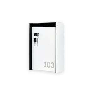 May include: A white key box with a black trim and the number "103" in gray. Two keys hang from the lock. The box is rectangular and mounted on a white background.
