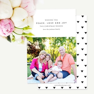 May include: A Christmas card featuring a family of four sitting on a blanket in a park. The card has a white background with black text that reads "Wishing you Peace, Love and Joy this Christmas Season love the Jackson family". The card also has a website address at the bottom: "westwillowdesigns.com".
