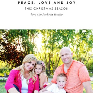 May include: A family of four, a mum, dad, and two children, are sitting on a white blanket in a grassy park. The parents are wearing casual clothing, while the children are wearing colourful shirts. The family are smiling and looking at the camera. The text "Wishing you peace, love and joy this Christmas season love the Jackson family" is displayed above the image.