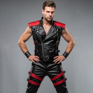 Könnte beinhalten: Schwarze Lederweste mit roten Schulterakzenten, kombiniert mit passenden schwarzen Lederhosen mit roten Riemen. Das Outfit umfasst einen Gürtel und Handgelenkmanschetten und erzeugt einen auffälligen, kantigen Look. Die Weste hat einen Reißverschluss.