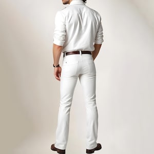 May include: A white button-down shirt with a brown leather belt and white jeans. The person is wearing a white shirt and white jeans.