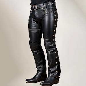 May include: Black leather pants with gold studs and a belt. The pants have a zipper detail on the side.