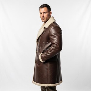 May include: A brown leather coat with a cream-colored shearling lining and trim. The coat features a double-breasted design with gold buttons and a wide lapel. The coat is knee-length and has pockets. The brand name "POSH BESPOKE LEATHER GOODS" is visible.