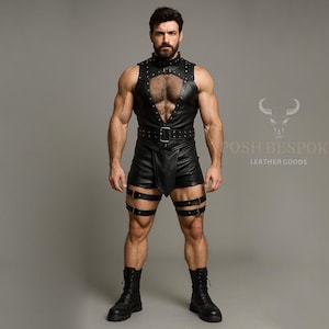 Pode incluir: Roupa de couro preta com um top sem mangas com tachas, uma cintura com cinto e calções a condizer. A roupa inclui cintas para as pernas e é combinada com botas pretas. A imagem também exibe o texto "POSH BESPOKE LEATHER GOODS".