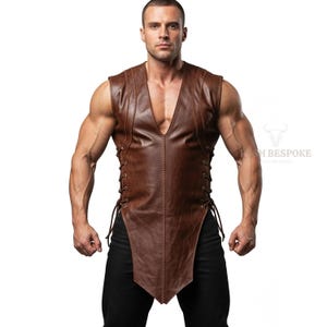 May include: A brown leather vest with a deep V-neck and side lace-up detailing. The vest has a tailored fit and a slightly asymmetrical hemline. The vest is worn over a black shirt.