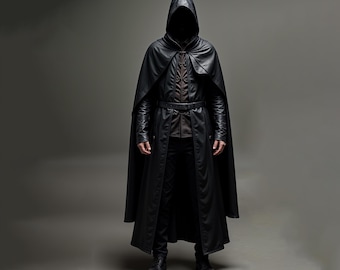 May include: A full-length black hooded cloak and coat ensemble. The coat features a belted waist and long sleeves. The outfit includes a brown shirt and black pants. The person is wearing black boots. The background is a solid gray.