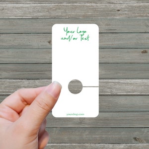 May include: White blank tag with a hole for hanging. The tag has a line at the bottom and the text "Your Logo and/or Text" at the top. The text "yourshop.com" is at the bottom of the tag.