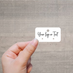 May include: White rectangular tag with rounded corners and three holes. The tag says "Your Logo or Text" in black cursive writing.