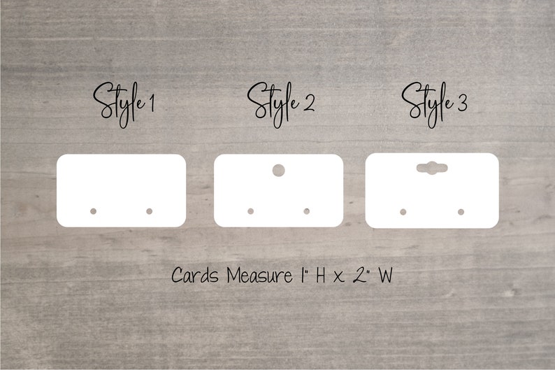 May include: Three styles of white earring display cards with holes for earrings. The cards measure 2.5 cm high by 5 cm wide. "Cards Measure 1" H x 2" W" is printed below the cards.
