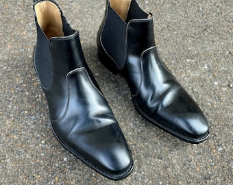 May include: A pair of black leather Chelsea boots with elastic side panels. The boots have a pointed toe and a low heel.