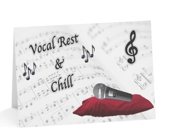 Op de afbeelding: Een witte kaart met de tekst "Vocal Rest & Chill" en een microfoon die op een rood kussen ligt. De achtergrond is een blad muziek met vioolsleutels en noten.
