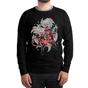 May include: Black sweatshirt featuring a cartoon illustration of two anime-style characters with horns, wings, and tails. The characters are in shades of red, pink, and blue, set against a white and gray background with star accents. The sweatshirt has a crew neck.