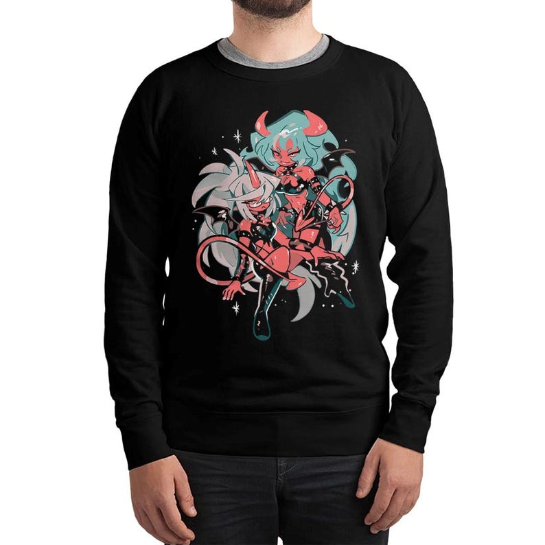 May include: Black sweatshirt featuring a cartoon illustration of two anime-style characters with horns, wings, and tails. The characters are in shades of red, pink, and blue, set against a white and gray background with star accents. The sweatshirt has a crew neck.