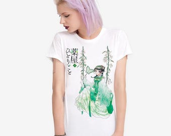 Puede incluir: Camiseta blanca con una ilustración de estilo anime japonés de una mujer con un vestido verde en un columpio con detalles florales. La camiseta tiene texto japonés en la parte delantera.
