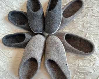 Puede incluir: Ocho zapatillas de fieltro gris dispuestas en círculo sobre un fondo blanco. Las zapatillas son todas del mismo estilo, con la punta redondeada y un diseño sencillo.