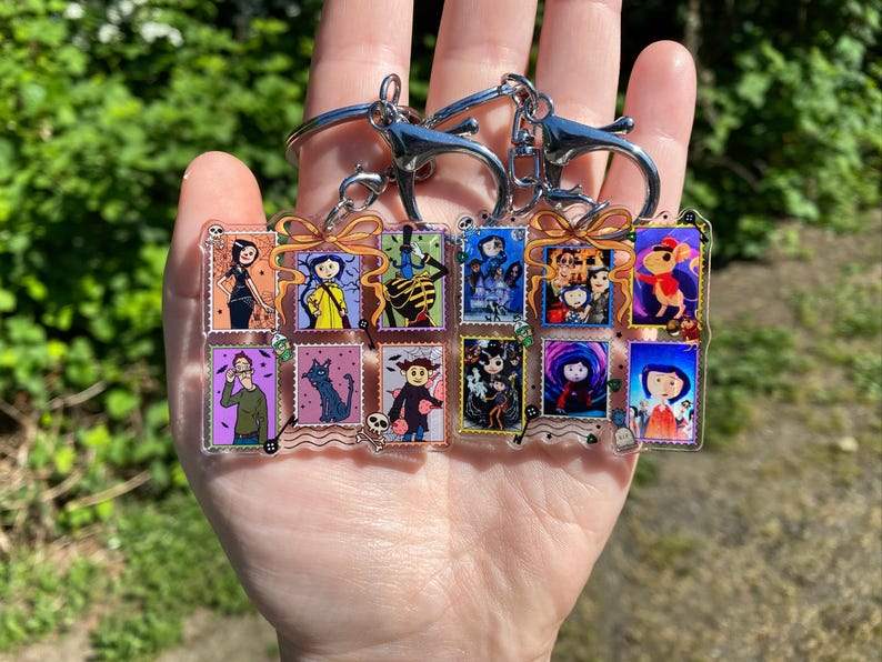 May include: A collection of keychains featuring colorful illustrations of characters from a fantasy movie. Each keychain has a silver clasp and a series of rectangular images with a bow design. The images depict various characters in different scenes.