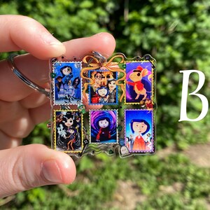 May include: A clear acrylic keychain featuring six colorful postage stamp designs with characters from a movie. The keychain has a silver-colored ring and a green and gold bow. The letter "B" is visible in the background.