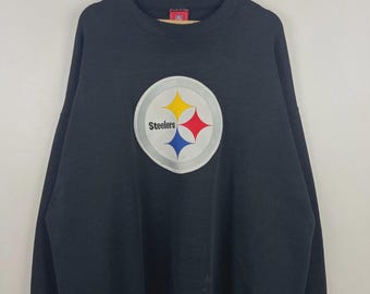 Puede incluir: Sudadera negra de cuello redondo con el logotipo de los Steelers de Pittsburgh. El logotipo es un círculo blanco con un borde plateado, que contiene diamantes amarillos, rojos y azules, con la palabra "Steelers" en negro.